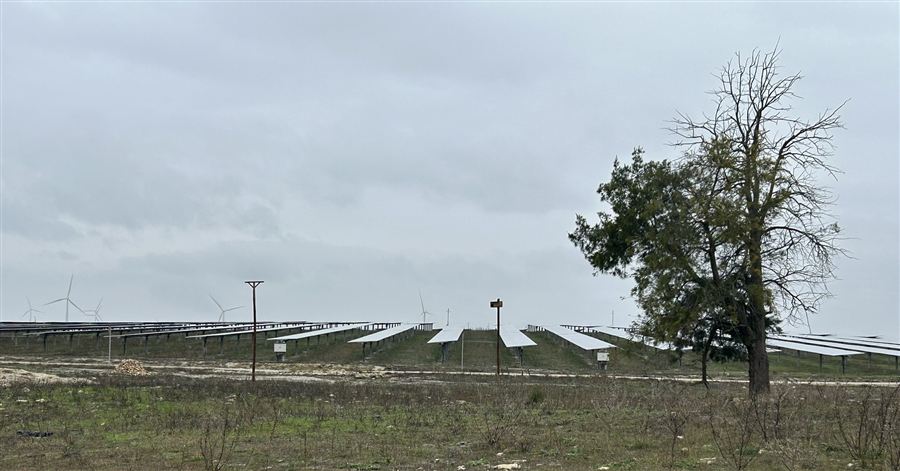 Planta solar con aerogeneradores al fondo