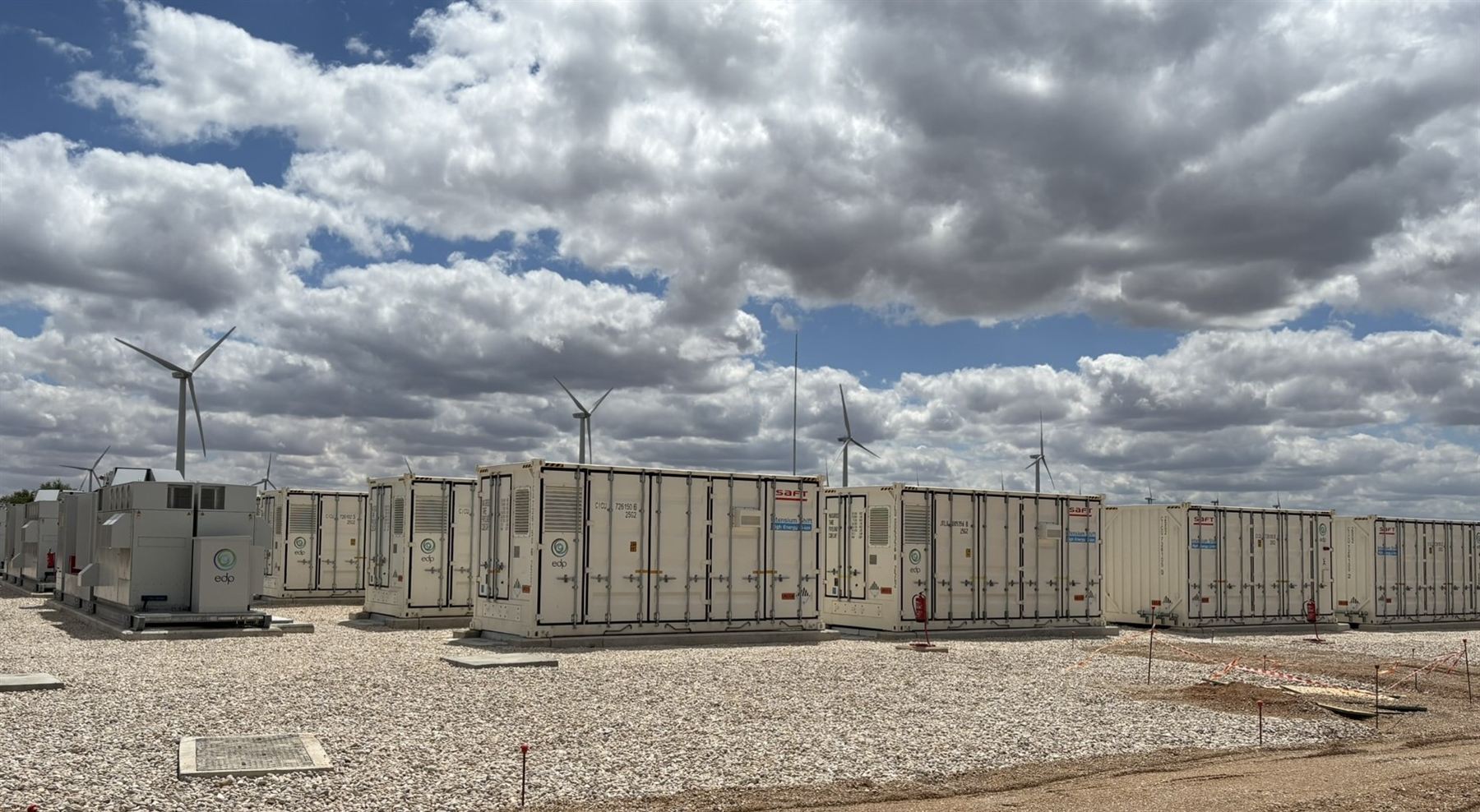 Contenedores de almacenamiento BESS con aerogeneradores al fondo