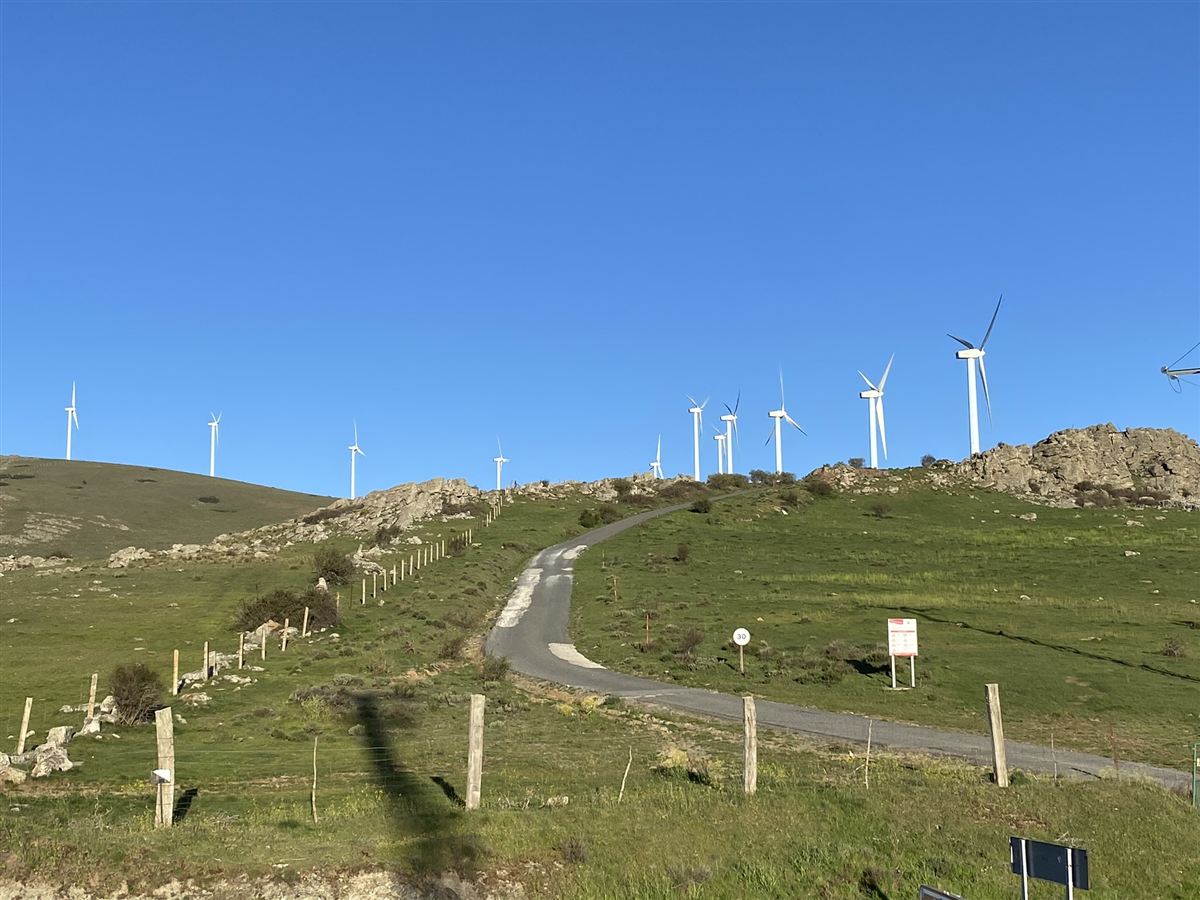 Camino de acceso a un parque eólico con aerogeneradores en ladera
